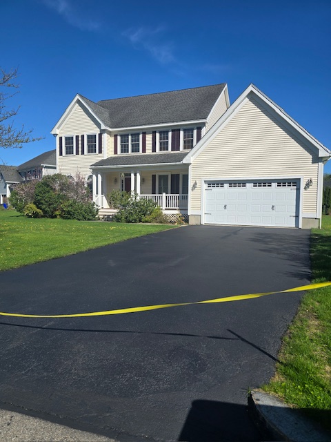 Freshly seal-coated driveway in front of two-car garage with double-wide garage door.