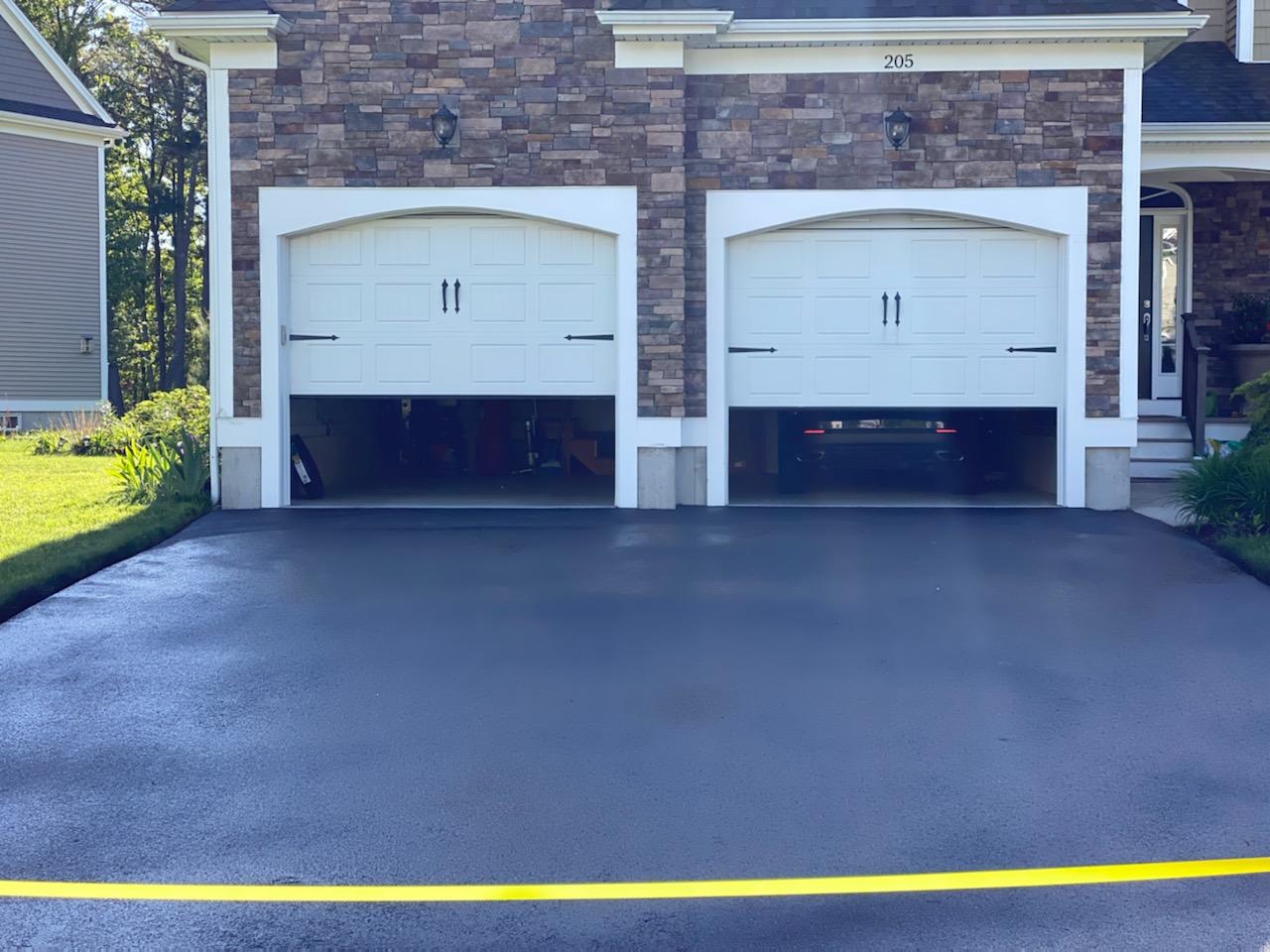 Freshly seal-coated driveway in front of two-car garage.